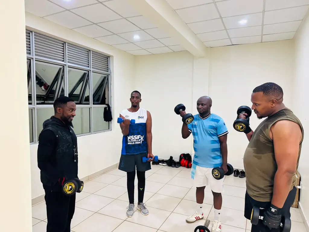 A coach watching three members do dumbbell curls